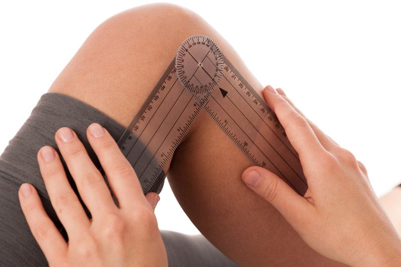 Therapist measuring the bend of a client's knee with a goniometer