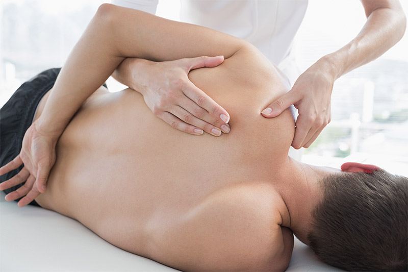 Physiotherapist treating a patient's shoulder with hands-on manual therapy