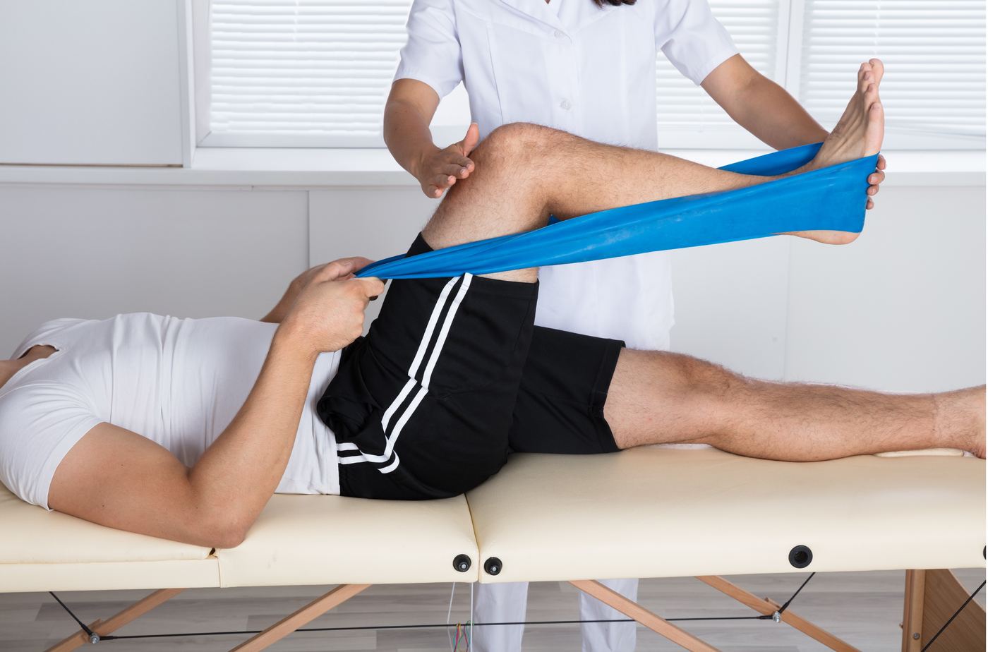 Physiotherapist guiding a patient through a leg stretch with a resistance band