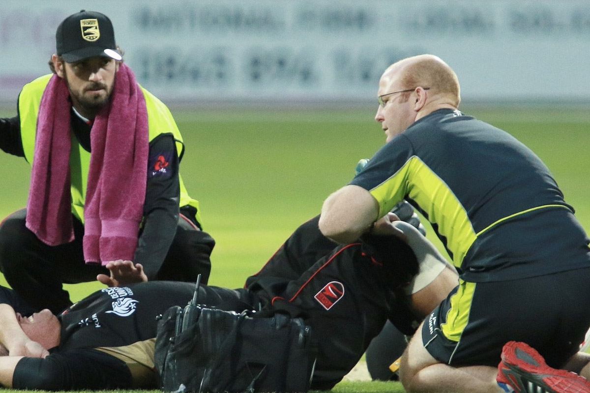 Rob Leather treating a Leicestershire cricketer on the pitch during a match