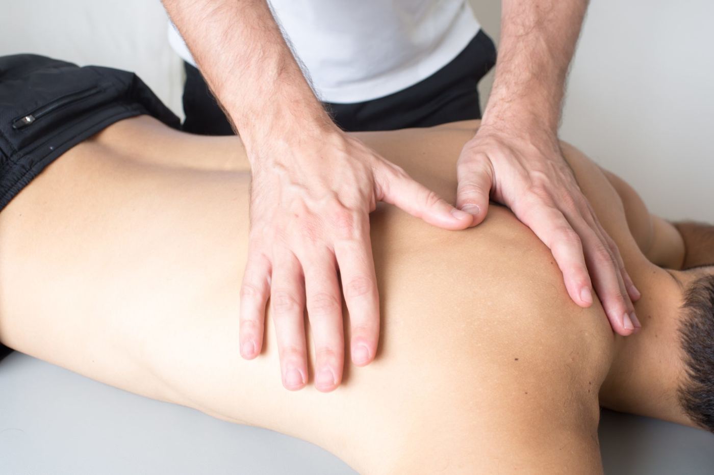 Physiotherapist mobilising a patient's upper back on a treatment couch
